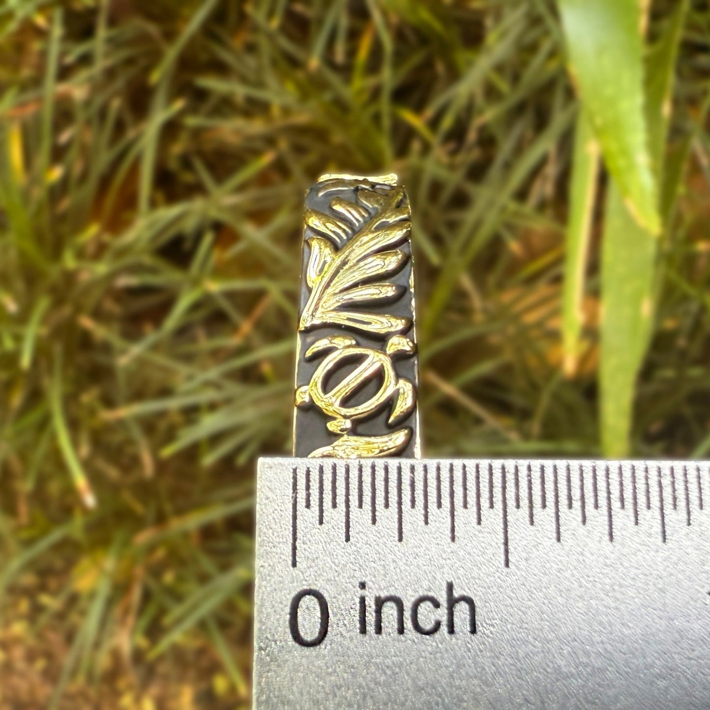 Bracelet with leaf pattern on a ruler against a natural background