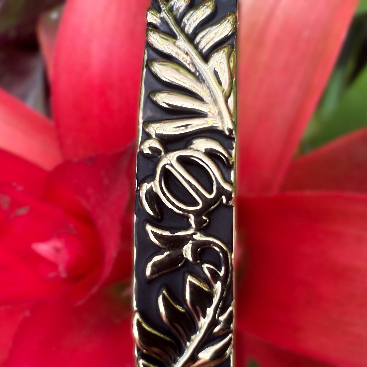 Bracelet with gold and black pattern against a red flower background