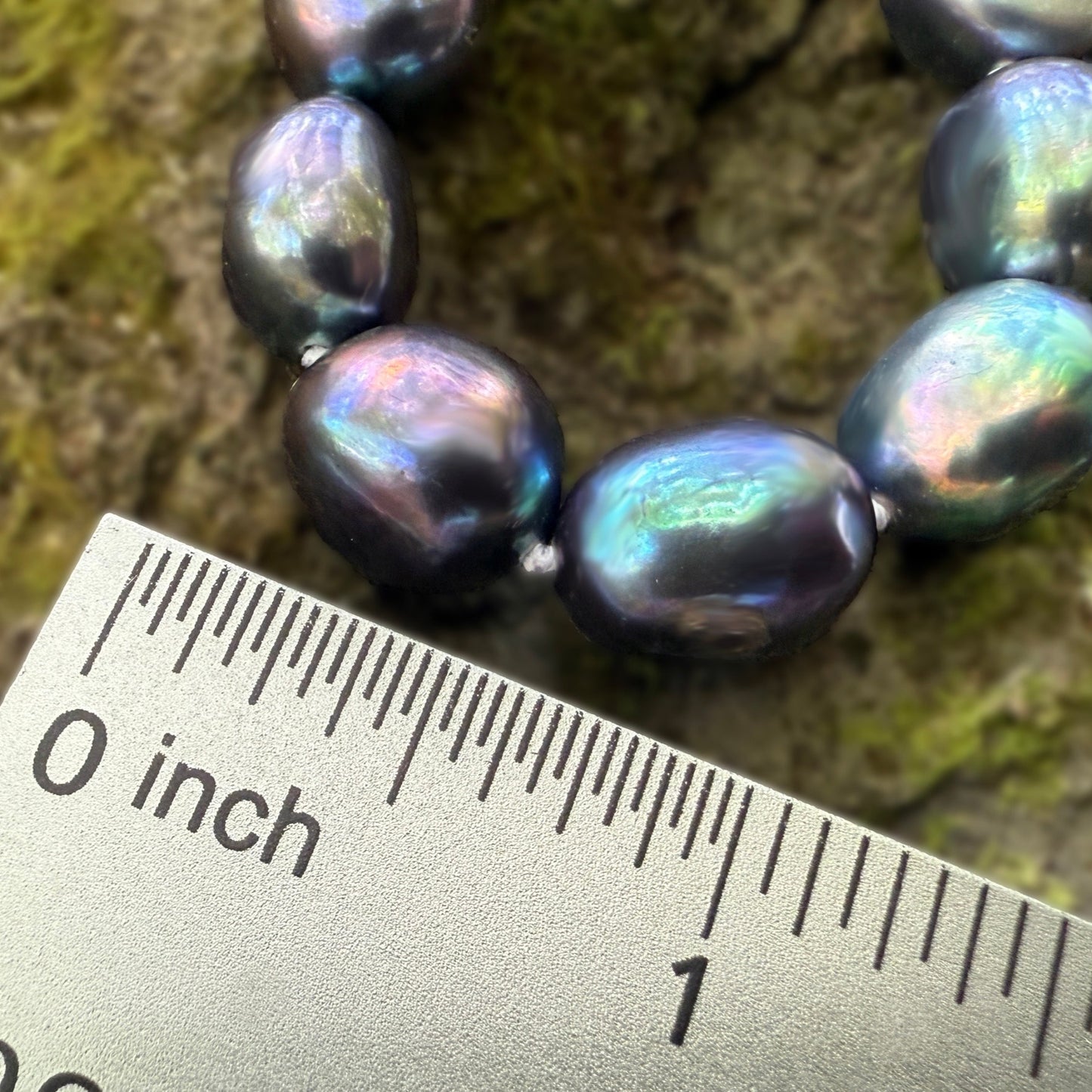 Pearl necklace on a textured surface with a ruler for scale
