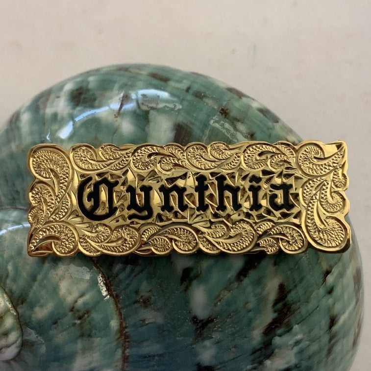 Nameplate with cutout scallop edge and black enamel lettering.