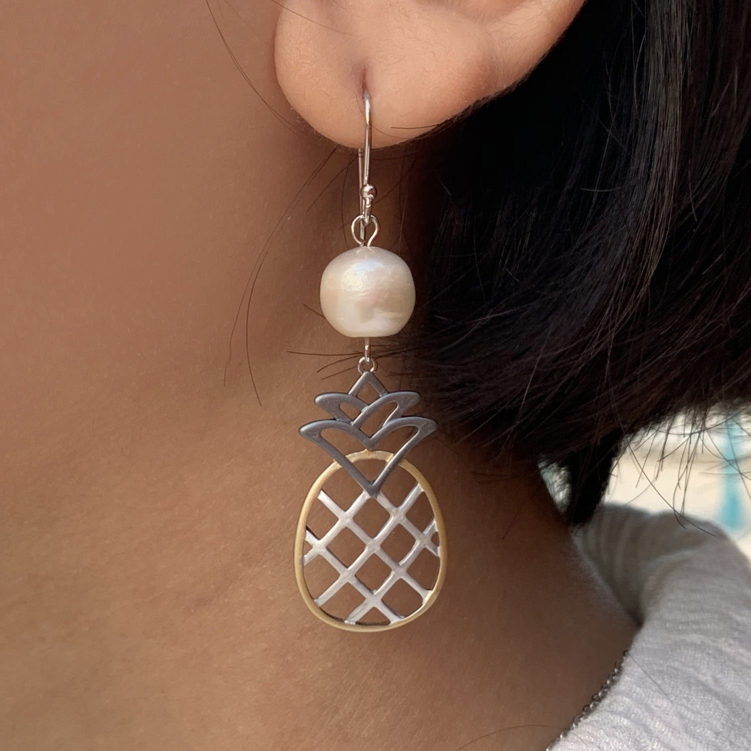 Close up of white pineapple pearl tri-color earrings on model