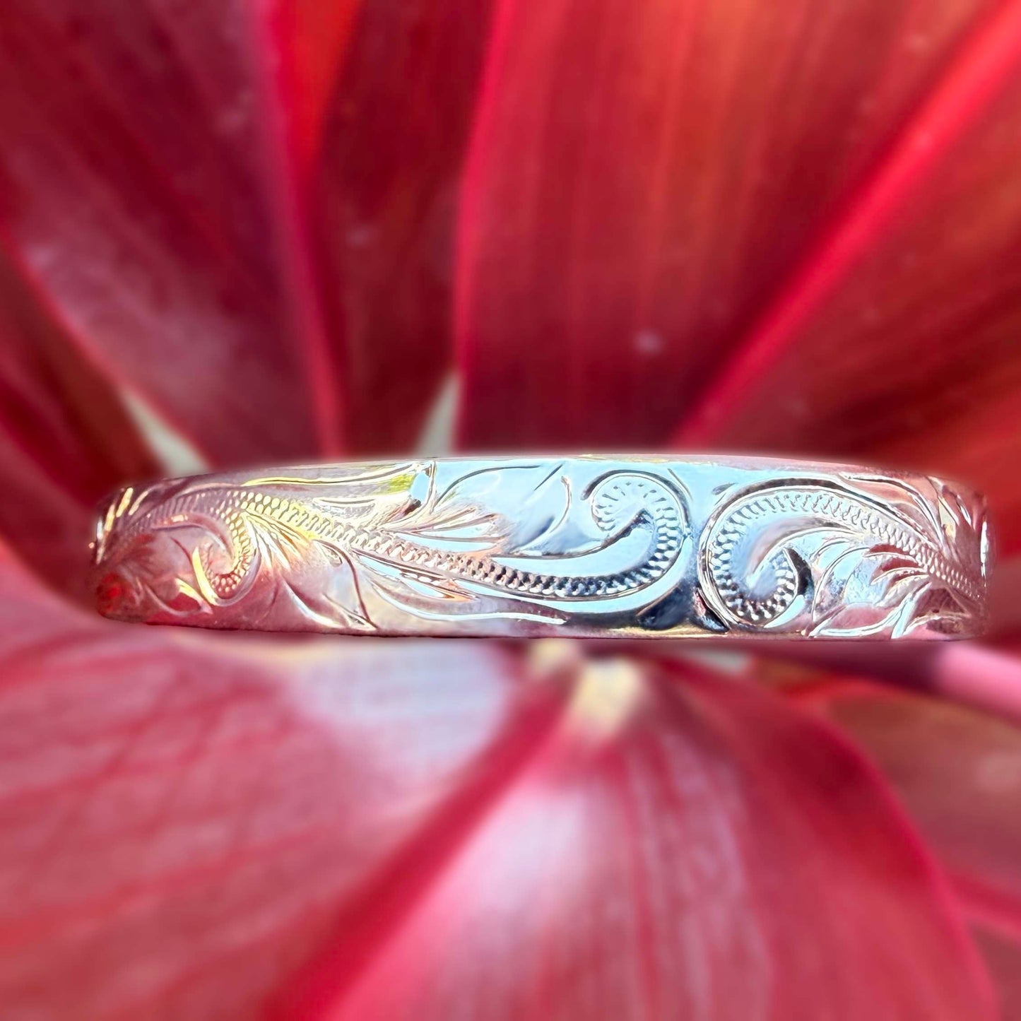 Silver ring with floral engraving on a red flower background