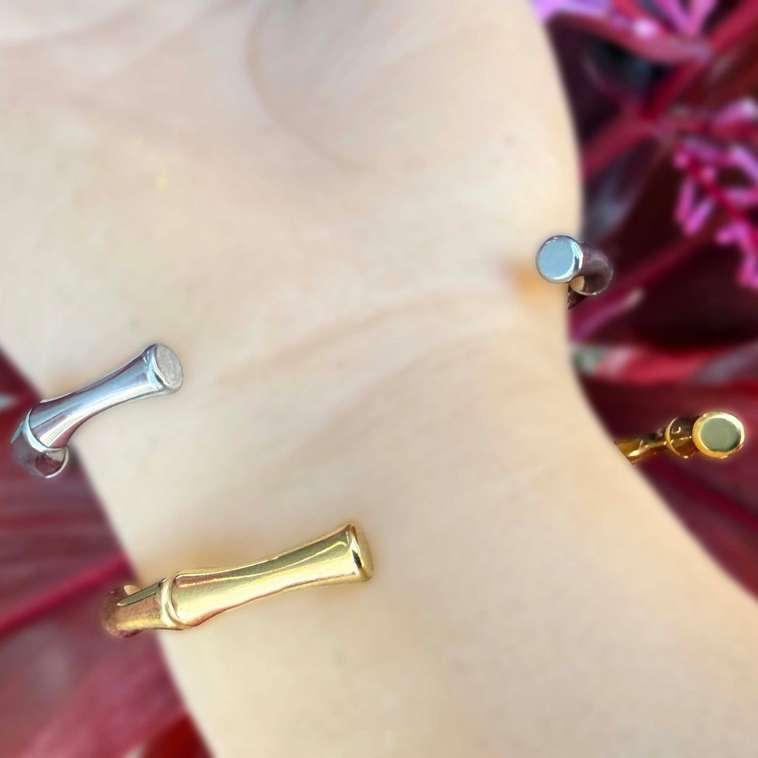 Gold and silver bracelets on a mannequin arm with a floral background