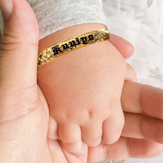 Baby Hawaiian heirloom bracelet with straight edge and black lettering on baby model.