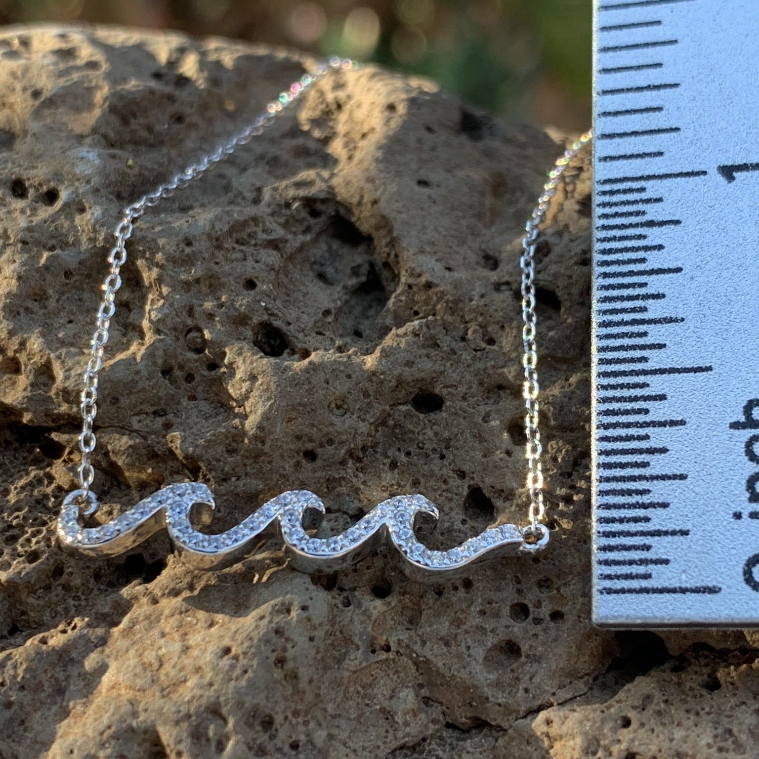 Crystal waves pendant in white caps with ruler measuring one inch.