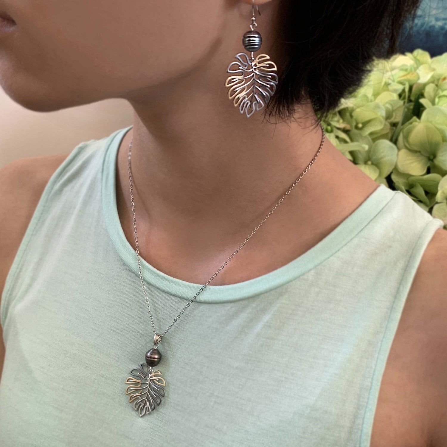 Monstera pearl pendant shown on model with earrings.
